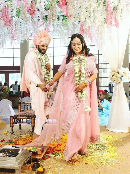 A candid moment during the wedding ceremony. The groom's elegant pink and white outfit is a popular choice for modern Maharashtrian weddings.