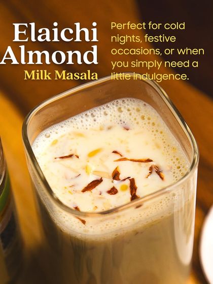 A close-up of a glass of rich and creamy Elaichi Almond Milk. Topped with slivered almonds, this drink, made with my special milk masala, is perfect for cold nights or festive occasions.