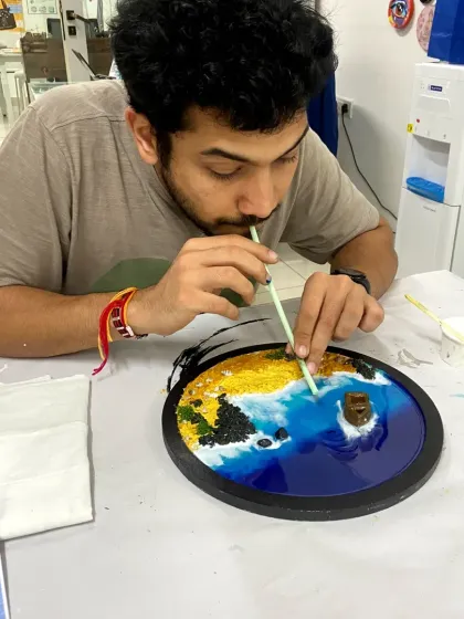A participant creates wave effects in his resin beach art. The hands-on process is both fun and educational.