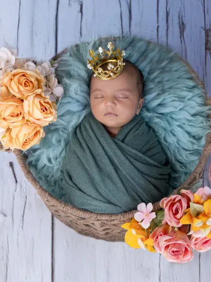 A tiny prince in his basket, complete with a crown. This shot shows how props can add a touch of royalty and fun to newborn photos.