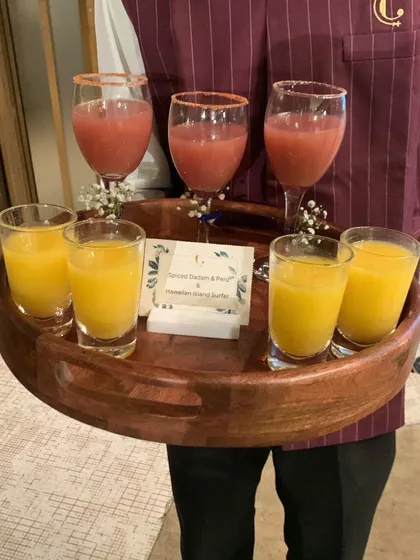 A server presenting a tray of our colourful mocktails. Our professional service ensures that guests are welcomed with a refreshing beverage upon arrival.