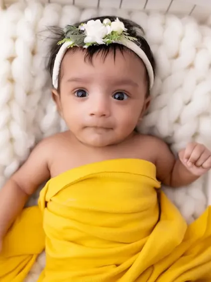 A sweet close-up of our little sunflower baby. Her bright, alert eyes and the floral headband make this a truly heartwarming newborn portrait.