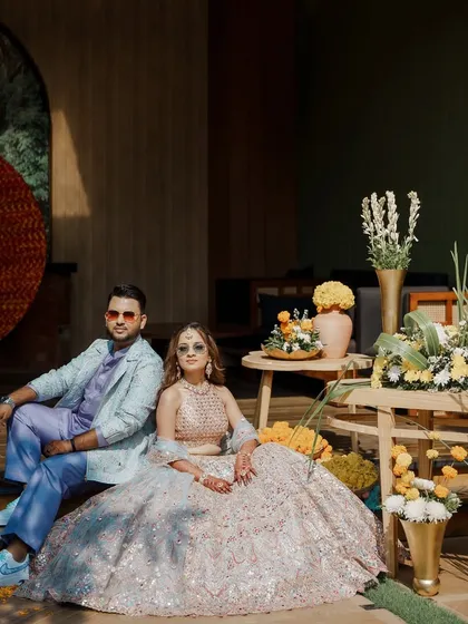 A full view of the couple's Haldi Carnival look. The groom's custom jacquard jacket and initialed sneakers add a sharp, personalized touch to his pastel ensemble.