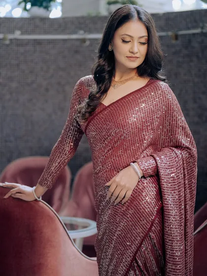 The rich color of the saree and the soft curls create a look of effortless glamour.