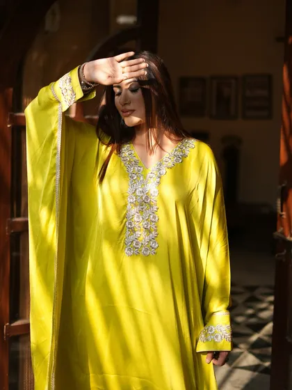 Another view of the sunlit lime green kaftan, emphasizing the beautiful handwork on the neckline.