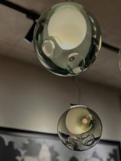 A close-up of three Bocci 28 pendants, showcasing the intricate "satellite" shapes within each glass sphere and the unique color variations.