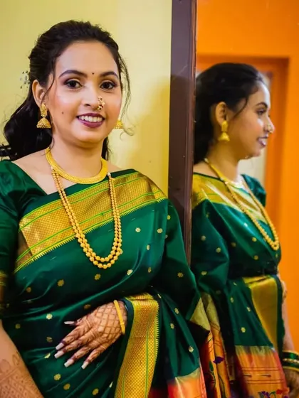 A lovely portrait of the bride, with her reflection captured in the mirror. She is wearing a traditional dark green Paithani saree, and I've given her a soft glam look for her engagement.