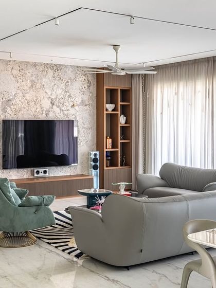 The living room from the 'Urban Oasis' project, showing a mix of textures and colors. A textured TV wall is flanked by wooden shelves, while teal armchairs add a pop of color.