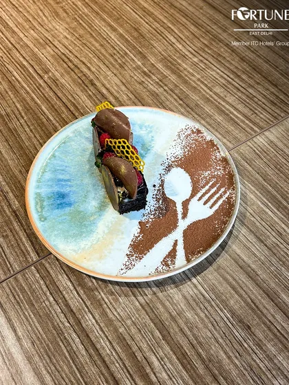 A rich chocolate dessert, artfully presented with cocoa powder stenciling and honeycomb decoration.