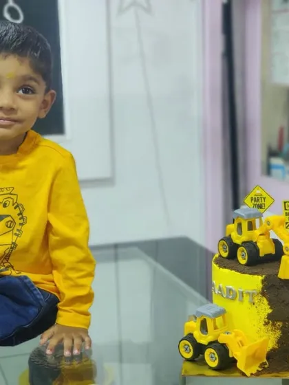 A young birthday boy posing proudly next to his construction-themed cake. We were so happy to make his special day even better.