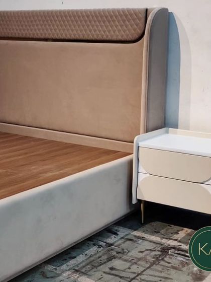 A custom bed with a unique headboard featuring a diamond-quilted top panel. The soft, neutral upholstery and clean lines make it a sophisticated and comfortable choice for a modern bedroom.