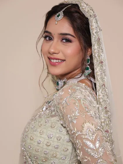 A soft and dreamy look created for a photoshoot. The pastel green lehenga is complemented by shimmery eye makeup and a natural lip, perfect for a bride who wants an ethereal and modern Nikkah or reception look.