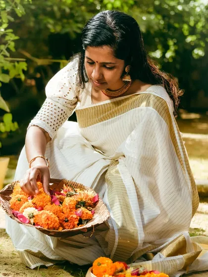 A personal photo from my Onam celebration, dressed in a traditional saree while arranging flowers. Sharing my own traditions is part of my story.