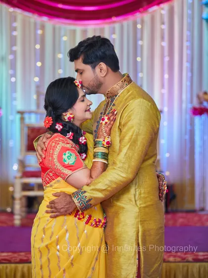 A tender moment between the couple during their Haldi ceremony. The groom kisses the bride's forehead, showing a quiet connection amidst the celebration.