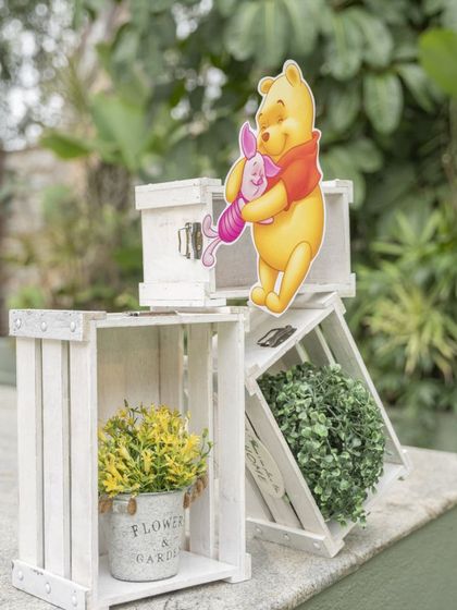 Rustic white crates with a Pooh and Piglet cutout, used as part of the entrance decor to build the theme from the moment guests arrived.