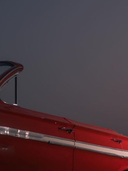 An intimate and romantic shot of the couple in a classic red car at night, creating a private and cinematic moment.