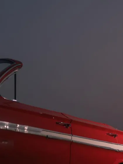 An intimate and romantic shot of the couple in a classic red car at night, creating a private and cinematic moment.