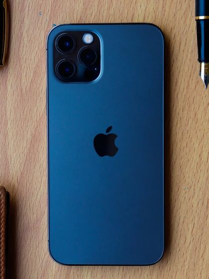 A classic flatlay of an iPhone on a wooden desk, flanked by elegant fountain pens and a leather wallet. This styling creates a sophisticated, professional, and masculine aesthetic.