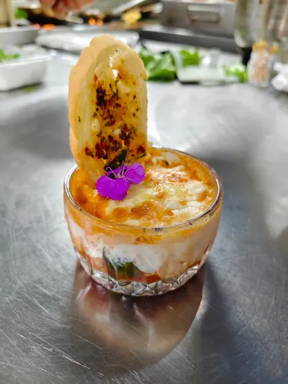 Baked bliss with a floral kiss. This individual portion of baked pasta is layered with cheese and sauce, then garnished with an edible flower for a touch of elegance.