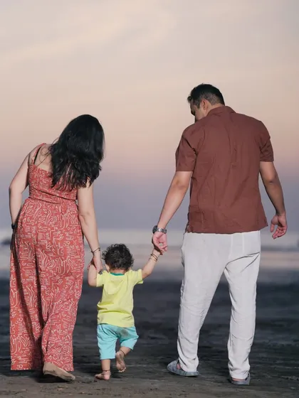 A lovely shot from behind, showing parents holding their child's hands as they walk on the beach. This image beautifully symbolizes guidance, support, and family unity.