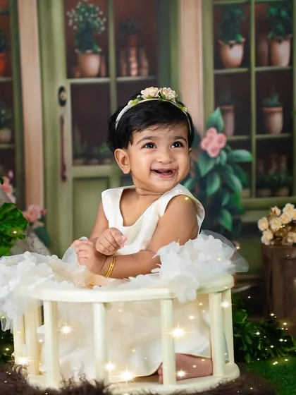 A joyful smile in a simple, rustic setting. The "ONE" sign and greenery create a lovely first birthday portrait.