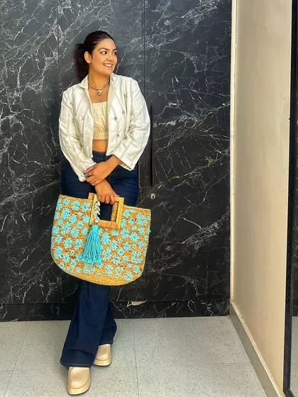 A full-length view showing how the handcrafted tote bag becomes the centerpiece of a chic, casual outfit. The wooden handles add an extra touch of rustic charm.