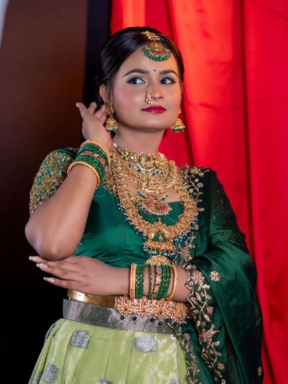 This green-themed bridal look features our heavy temple jewellery set with a prominent deity pendant, paired with a matching maang tikka and jhumkas.