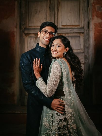 A beautiful couple portrait from a sangeet or reception. The bride's makeup is soft and glamorous, with a focus on her radiant smile.