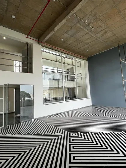 A wide view of the double-height social space in "The Treehouse" during construction. The large window wall connects this interior space to the city beyond.