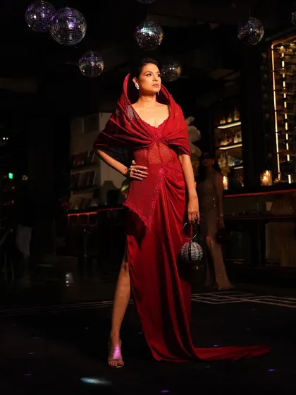 Power and poise converge in this crimson red slit gown. The structured hood adds a touch of unapologetic glamour, designed for nights filled with drama and detail.