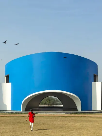 A child runs towards the bright blue amphitheater, a perfect image of how architecture can inspire joy and playfulness in learning environments.