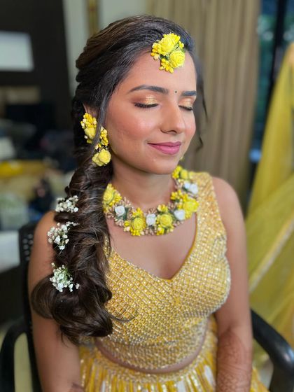 A happy bride at her Haldi function. The makeup is fresh and minimal, with a beautiful braided hairstyle.