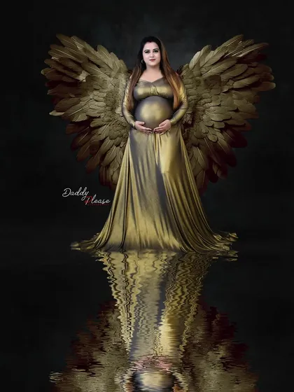 A powerful and angelic portrait of a mother-to-be in a metallic gold gown with matching wings, reflected in the water below. This image represents the goddess-like, fine-art style I offer in my studio.