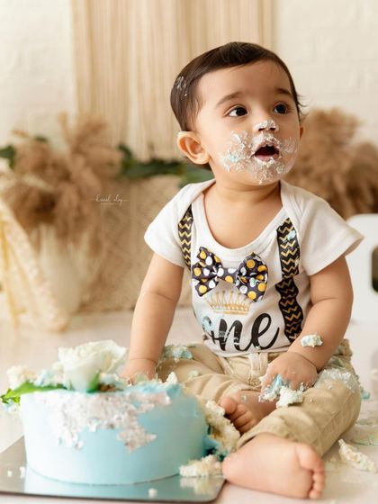 This little one is looking up, perhaps asking for more cake, during his first birthday photoshoot.