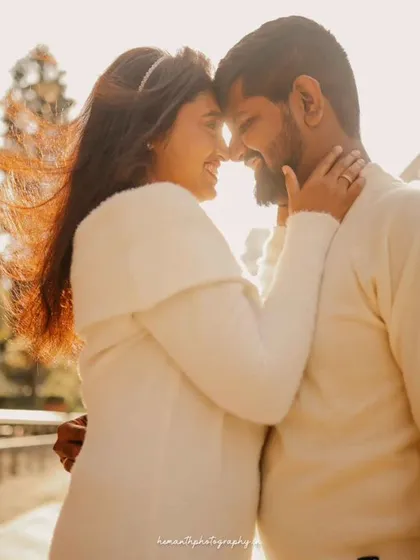 A romantic, sun-flared shot of a couple about to kiss, set against a modern city backdrop during the golden hour.