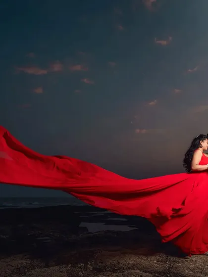 Create a dramatic and romantic pre-wedding photo with our signature long-tail gowns. This vibrant red gown provides a stunning contrast against the evening sky.