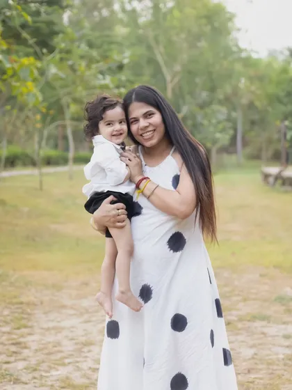 A smiling mother holds her toddler, both looking directly at the camera. This photo shows how we can capture both posed and candid moments during a single outdoor session.