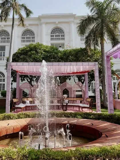 A wide view of the beautiful garden Mehendi setup, with the venue's fountain as a central feature, surrounded by pastel canopies and elegant seating.