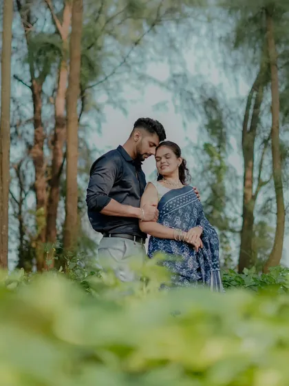 A romantic pre-wedding photo in a forest, where the groom tenderly holds the bride. The natural foliage creates a beautiful frame.