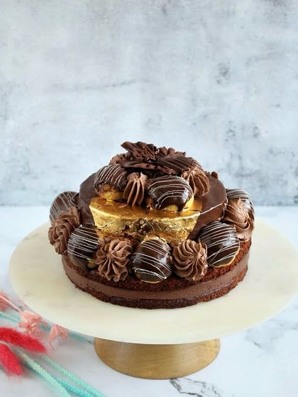 Another look at our Desire 3 Cake, standing tall on a marble platter. The combination of chocolate-dipped choux buns, gold varak, and rich mousse makes it a true work of art.