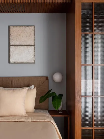 A guest bedroom featuring a bed with a handwoven headboard. The neutral tones and natural textures create a calm and inviting atmosphere for guests to rest and recharge.