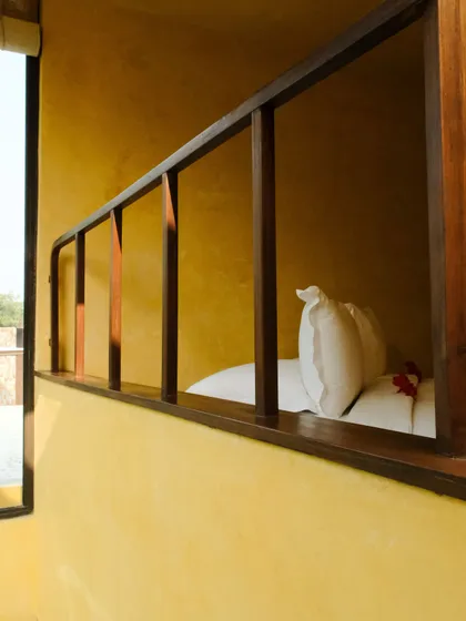 A detail of a suite's interior, showing the wooden railing and a glimpse of the comfortable bed, all bathed in warm, natural tones.
