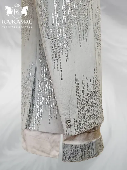 A detail shot of the lower part of the sequined white jacket, showing the texture and shimmer of the craftsmanship.