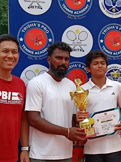 Academy player Yashas with his coaches after winning a championship. Our coaching team provides courtside support and strategic guidance during tournaments.