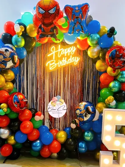 An action-packed superhero birthday party theme. We created this exciting backdrop with a full balloon ring, character balloons of Superman and Spider-Man, a neon "Happy Birthday" sign, and a large marquee number '5'.