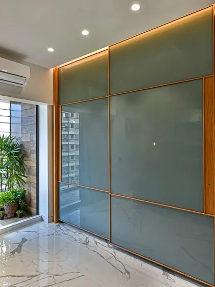 This bedroom uses a combination of wood and frosted glass for the wardrobe, creating a light and modern feel. The attached balcony brings in natural light and offers a private outdoor connection.