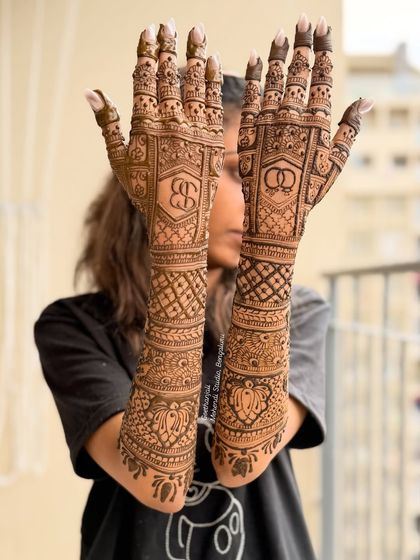 A creative pose showing off the full length of the engagement mehendi, with the couple's initials prominently displayed.