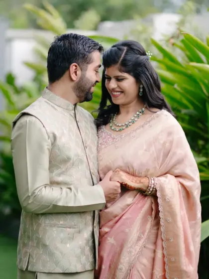 A sweet and gentle portrait of a couple holding hands, dressed in elegant pastel outfits for their engagement ceremony.