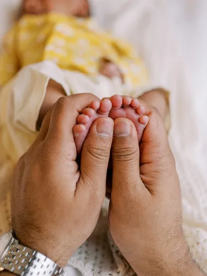 A father's hands gently holding his newborn's tiny feet. A simple, powerful image that speaks volumes about love and protection.