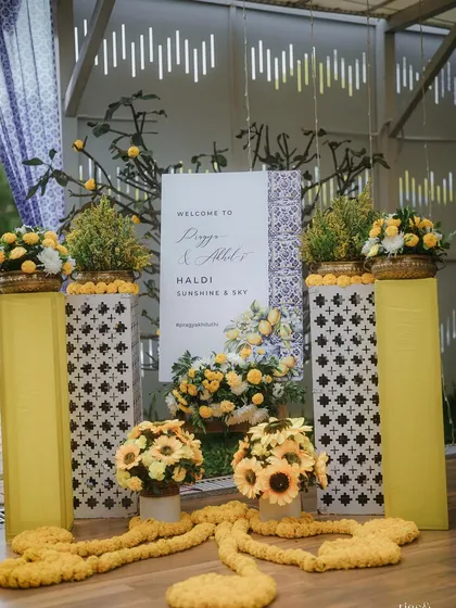 A personalized welcome sign for Pragya and Akhil's "Haldi, Sunshine & Sky" event. We used a cheerful yellow and white color palette with sunflower accents to match the theme.